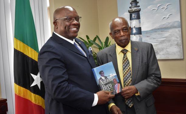 SIR KENNEDY SIMMONDS PRESENTS AUTOGRAPHED COPY OF HIS AUTOBIOGRAPHY TO PRIME MINISTER HARRIS